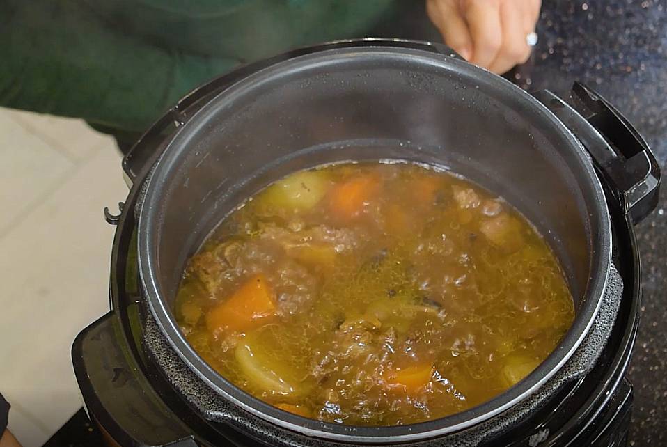 opening the pressure cooker to reveal the oxtail soup